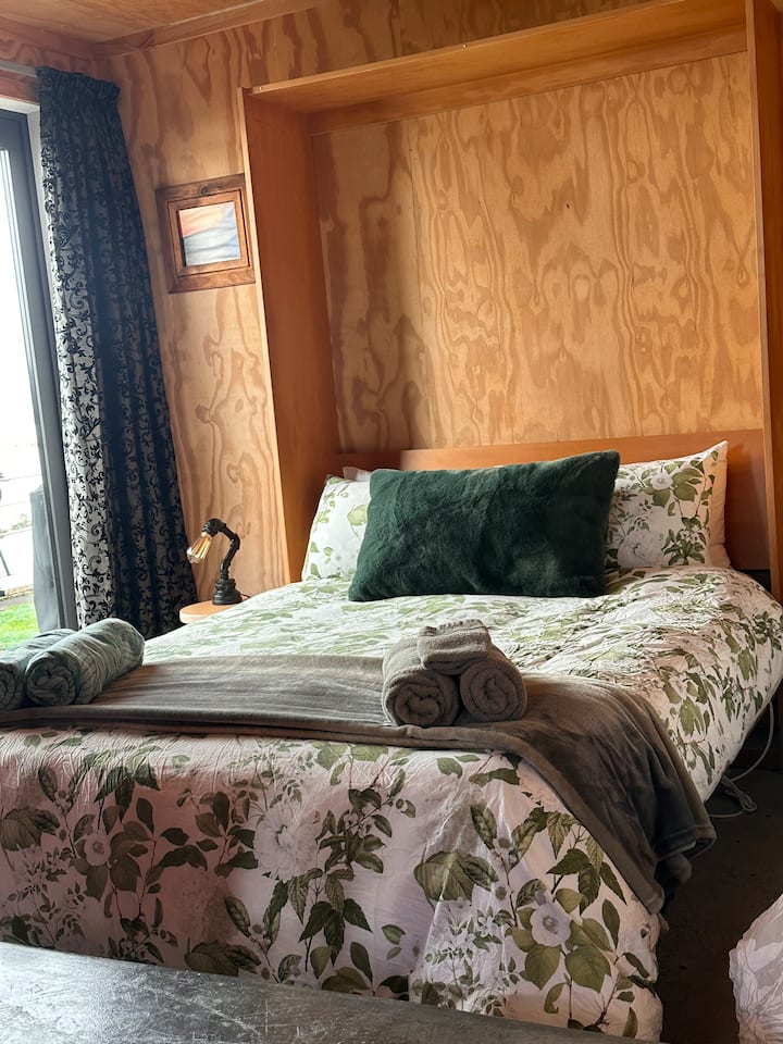 Gezellige slaapkamer met uitklapbaar bed
Verzonken slaapkamer net buiten de woonkamer, met een dik gordijn voor privacy. Comfortabel en uitnodigend voor een rustgevende nacht.