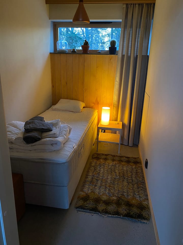 Krevati kontinental, komodina e vogël me sirtarë dhe grila me rulante janë në këtë dhomë më pranë hyrjes. 