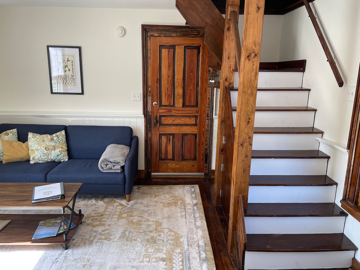 Living room with fold out couch and stairs leading to bedroom and bathroom. 