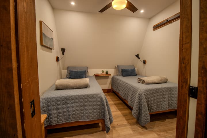 Two twin beds with private door and small closet for clothing storage. This room also has a ceiling fan and is located across from the bathroom.