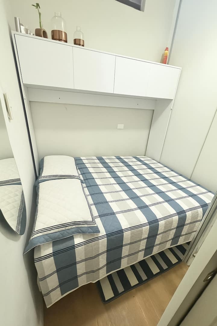 غرفة صغيرة، ولكنها مصممة بسرير مزدوج مفصلي ومريح مع خزانة ملابس.