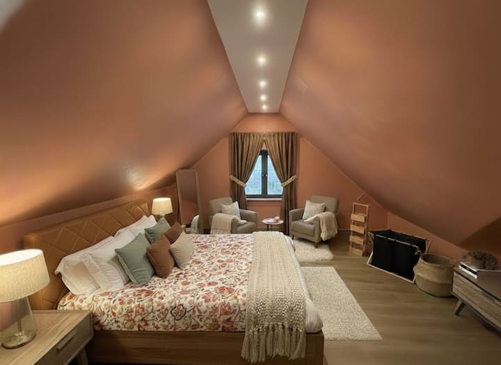 جناح علية واسع مع جدران تاديلاكت مغربية تقليدية وإضاءة دافئة. تخلق المقاعد المريحة والملمس الناعم والألوان الترابية ملاذًا هادئًا مستوحى من الحرفية المحلية والراحة الحديثة.