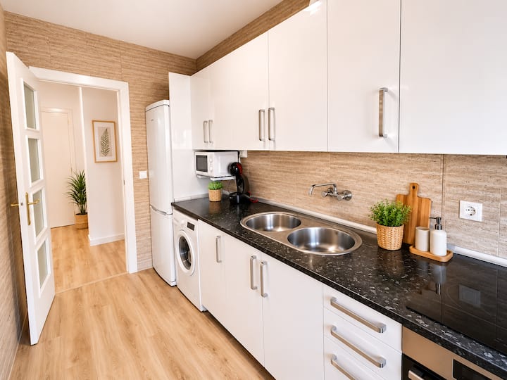 Cocina independiente con muebles blancos y encimera oscura
