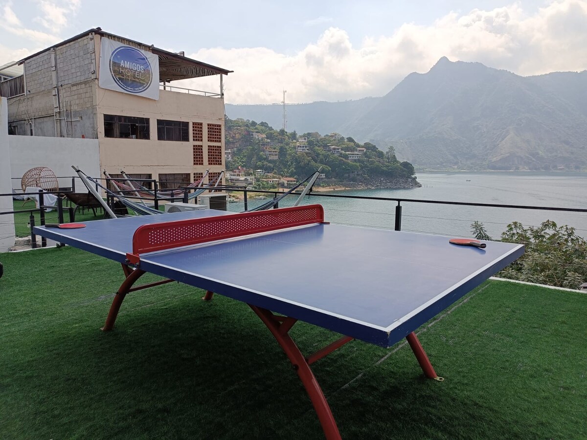 A spacious rooftop area features a well-maintained ping pong table, positioned to offer stunning views of the surrounding mountains and lake. The green grass-like surface enhances the inviting atmosphere while providing a recreational space for guests to enjoy.