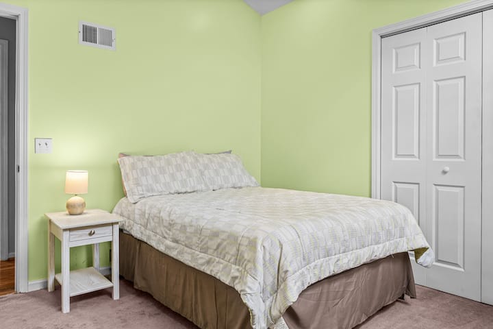 Green room with a full bed and closet.