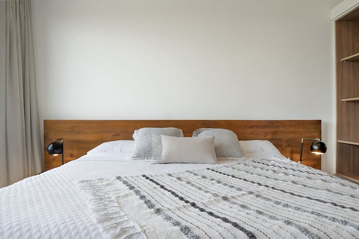 Chumba kikuu cha kulala chenye kitanda aina ya king, bafu la chumbani na kiyoyozi, mapumziko ya amani baada ya siku ufukweni.