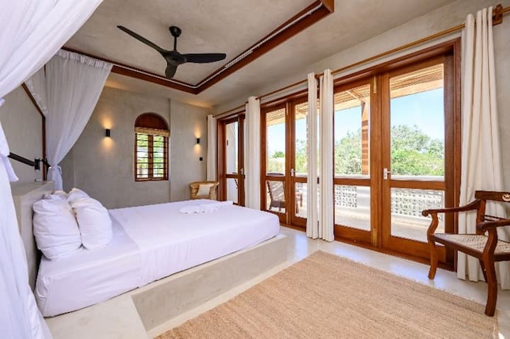 Dormitorio principal Waridi South. 1 cama doble grande con baño privado con ventilador y aire acondicionado.  Acceso a un balcón privado.  