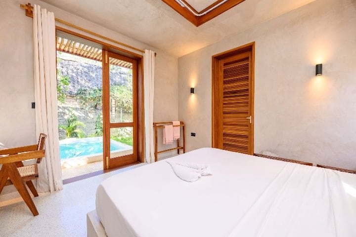 Un gran dormitorio doble con baño privado con vistas a la piscina de inmersión del lado norte. La habitación cuenta con aire acondicionado, ventilador y escritorio.