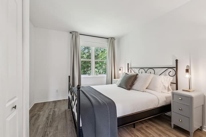 Este dormitorio trasero en el último piso cuenta con una cama tamaño queen, un tocador, un clóset, un ventilador y vista al bosque