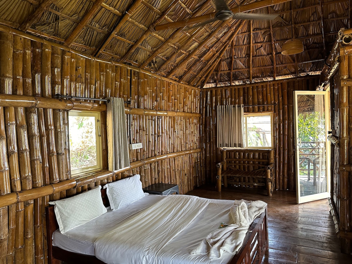 เฟอร์นิเจอร์ไม้ไผ่ที่อบอุ่นเต็มไปด้วยห้องนอนที่กว้างขวางให้สถานที่พักผ่อนที่เงียบสงบท่ามกลางเนินเขา Panchalimedu แสงธรรมชาติส่องเข้ามาในห้องผ่านหน้าต่างบานใหญ่เชิญชวนให้เกิดความเงียบสงบกลางแจ้ง