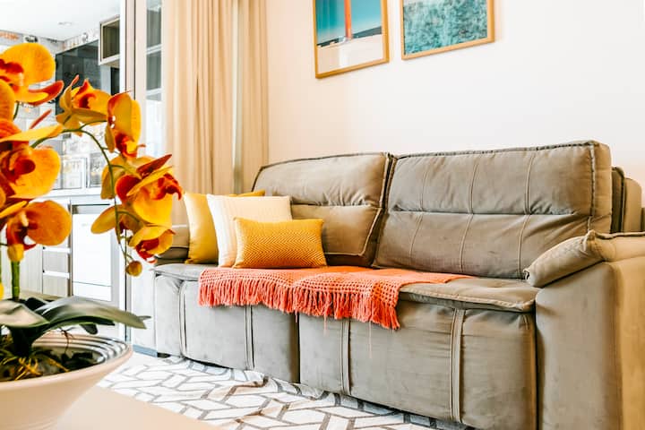 Smuk stue med kæmpe dobbelt sofa, dekoration i farverige nuancer, der bringer komfort og glæde til gæsterne
