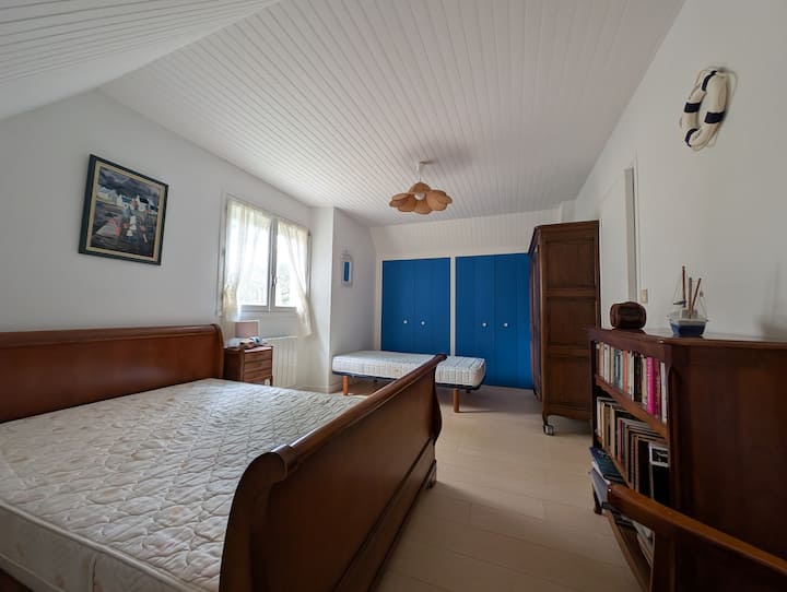 Gran dormitorio luminoso con una cama de matrimonio, una cama individual y un amplio armario con perchero