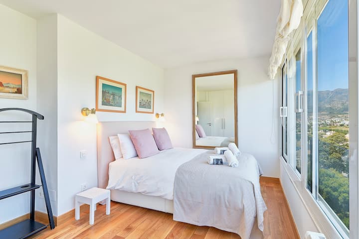 Dormitorio principal con cama doble, amplios ventanales y espectaculares vistas a las montañas. Un espacio lleno de luz natural, diseñado para ofrecer descanso, confort y tranquilidad. by Groway Home