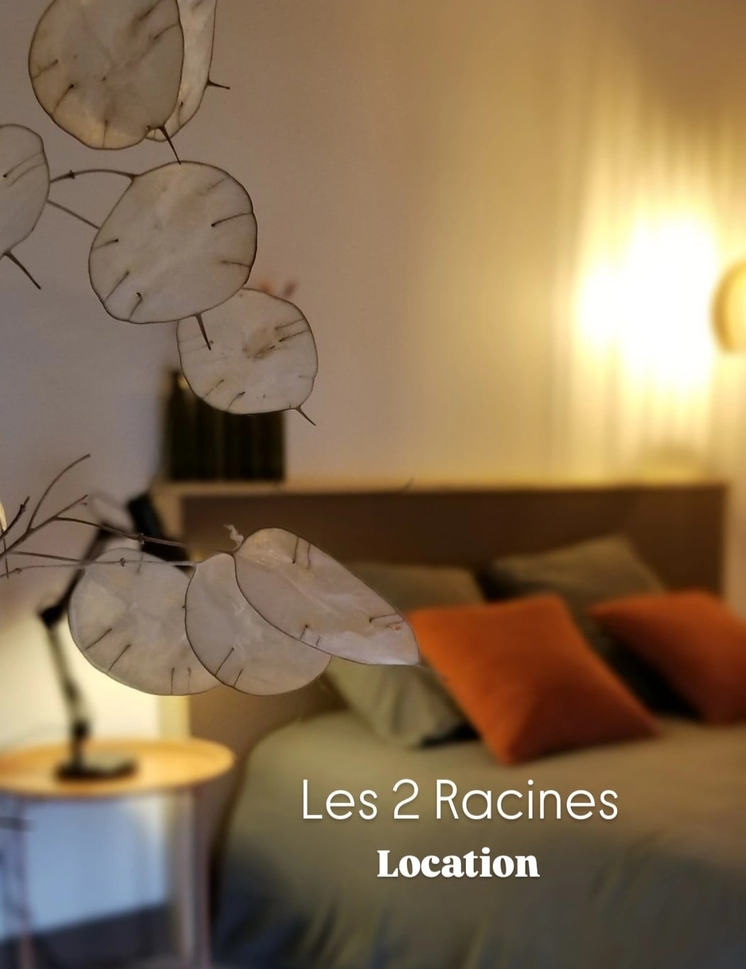 A calming bedroom scene is presented, featuring a spacious bed adorned with soft bedding and accent pillows. A side table with a lamp is positioned nearby, while the gentle glow of warm lighting enhances the serene ambiance of the space.