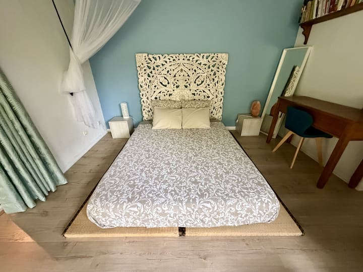 Suite principal con cama doble, cabecera esculpida, escritorio y decoración acogedora.