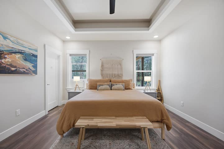 Primary bedroom. The room has a desk for remote work, large tv, walk in closet and a private bathroom equipped with a full soaking tub, tiled shower, double sinks and mirrors in vanity and a toilet with a sliding pocket door for privacy.