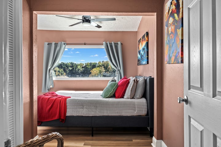 The Pirate Room features a cozy queen bed, a picture window overlooking the lake, a bookshelf for quiet moments, and a TV for streaming your favorite shows after a day on the water.