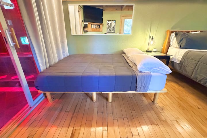 أريكة نوم قابلة للطي بالحجم الكامل (يتم توفير البياضات/البطانيات/الوسائد عند الطلب) مع طاولة بجانب السرير، وضوء قراءة يعمل باللمس مع توصيلات USB لشحن الهاتف، ومولد ضوضاء أبيض. 