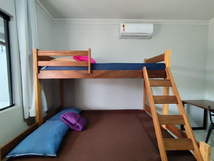 Spálňa s poschodovou posteľou: manželská posteľ dole a jednolôžko hore. Pracovný priestor, priestor na uloženie oblečenia s vešiakom a klimatizácia.