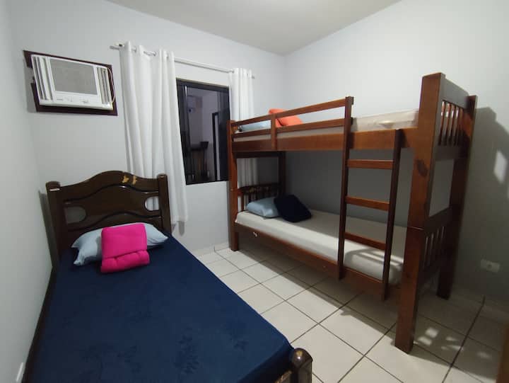 Spálňa s poschodovou posteľou a ďalším jednolôžkom, klimatizovaný priestor a vešiak na oblečenie.