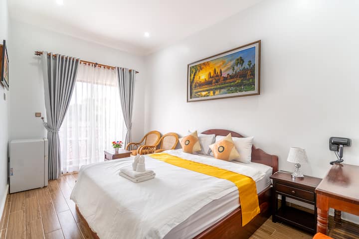 Cama con sofá y vistas al balcón,