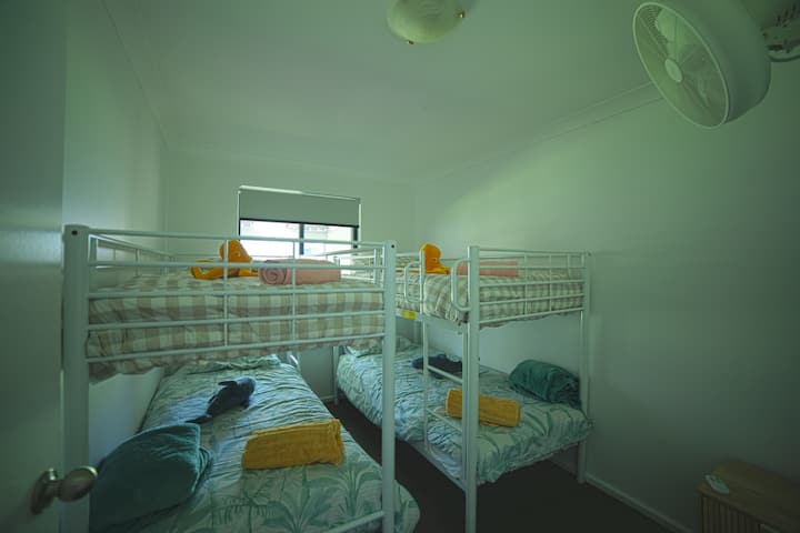 Two bunk beds, wall fan and block out blind to the window