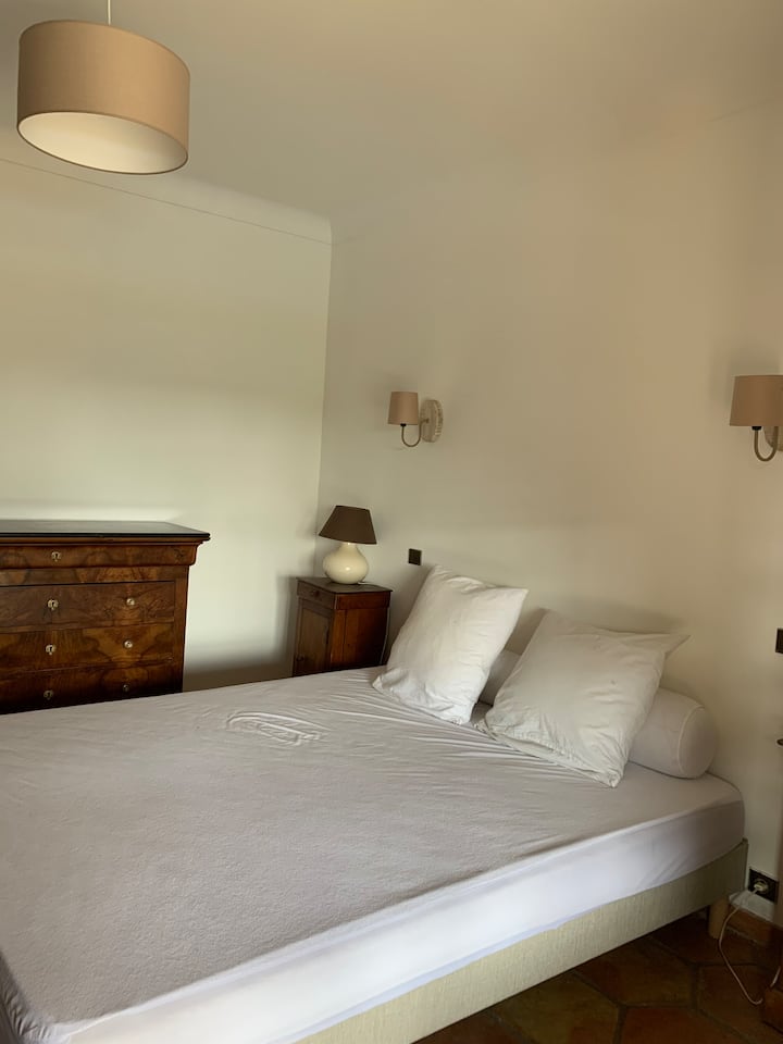 Habitación con cama queen size, vestidor y cómoda con acceso a pie al lado de la piscina a través de una terraza cubierta 