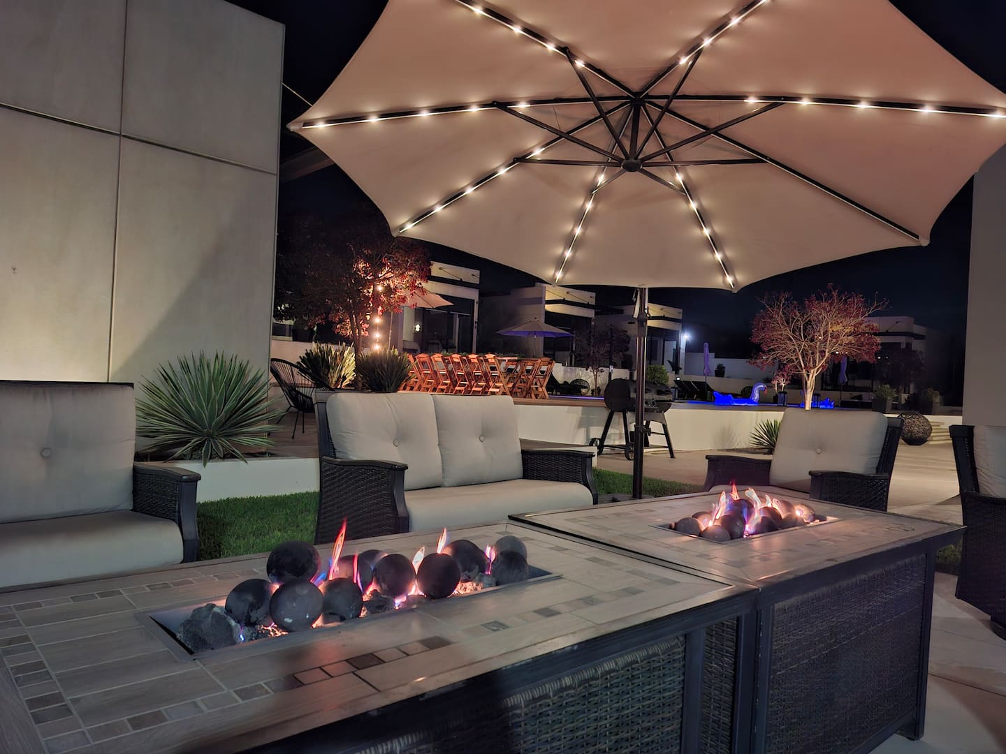 The patio fire pit under an umbrella strung with lights