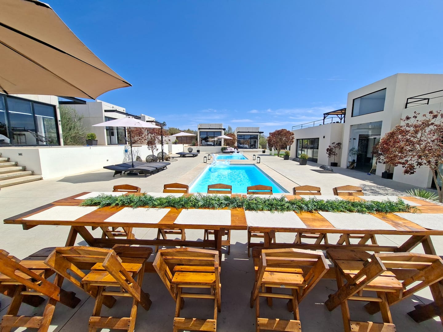 A long table set for a dinner beside the pool