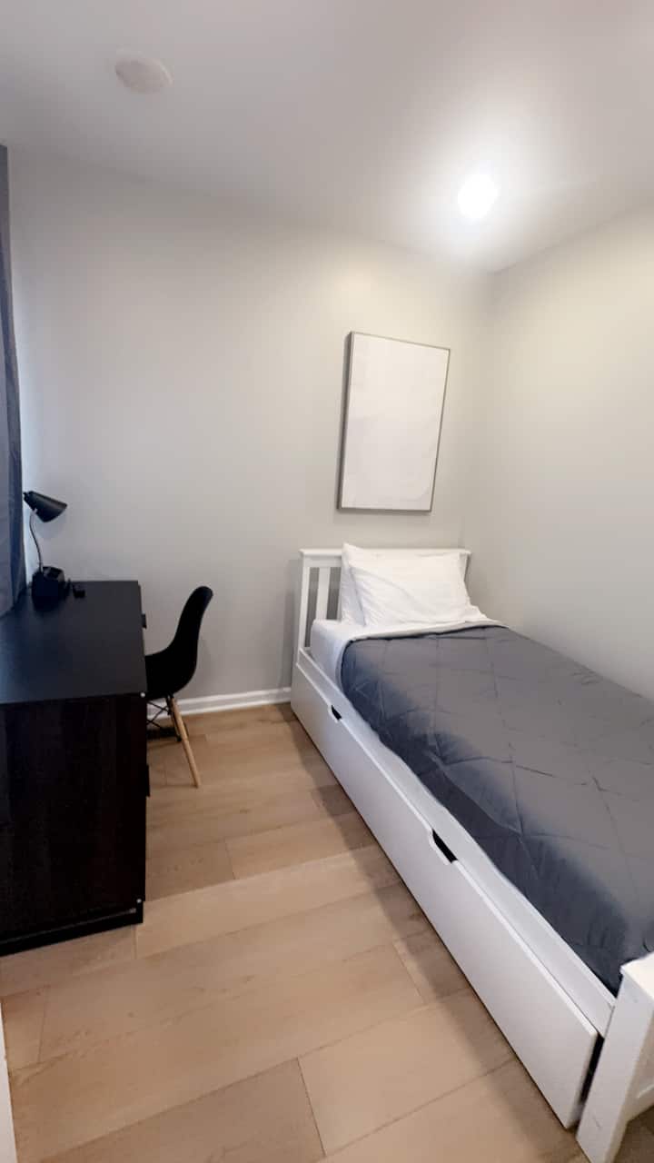 חדר שינה נעים עם מיטה זוגית עם מזרן נשלף נוסף, שולחן עבודה נוח וטלוויזיה עם מסך שטוח - אידיאלי לנוחות, פרודוקטיביות ורוגע.