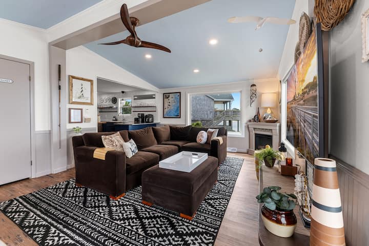 Comfortable open-plan living room with vaulted ceilings, sectional sleeper sofa, and electric fireplace.