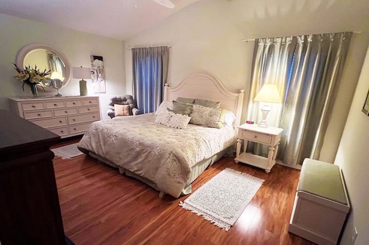 غرفة نوم رئيسية واسعة مع أرضية من الخشب الصلب، وخزانة ملابس، وخزانة ملابس، وكرسي سهل. تحتوي جميع غرف النوم الثلاث على ساعات منبه. استمتع بنوم هادئ في حي هادئ.