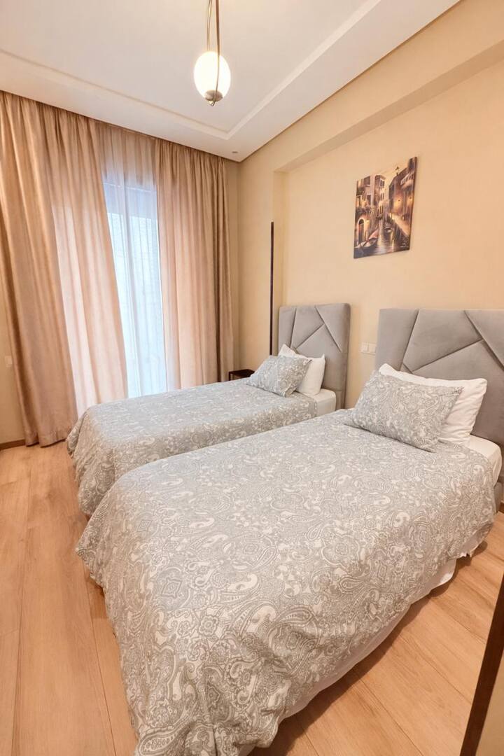 Segundo quarto com duas camas confortáveis, ideal para crianças, amigos ou viajantes que compartilham a acomodação. Cortinas blackout e espaço de armazenamento para uma boa estadia.