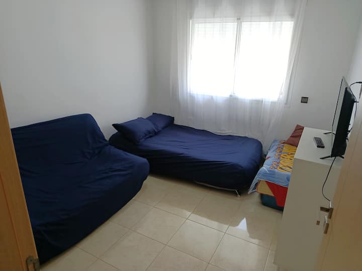 habitación con dos sofás cama, televisión y clóset