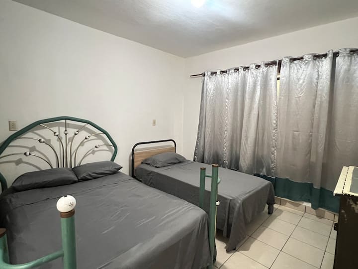 Kamer met tweepersoonsbed en eenpersoonsbed, gordijn.