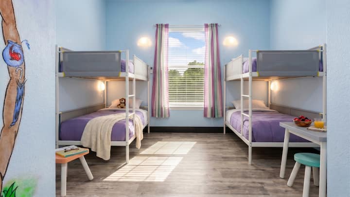 Kids will love this bright bunk room at Brazos Breeze, featuring two bunk beds with cozy bedding, cheerful light blue walls, and a cute little activity table perfect for snacks or games.