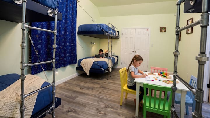 Kids will love this fun bunk room at Brazos Breeze, featuring custom built-in beds with industrial pipe ladders, and a colorful activity table perfect for arts, crafts, and games.