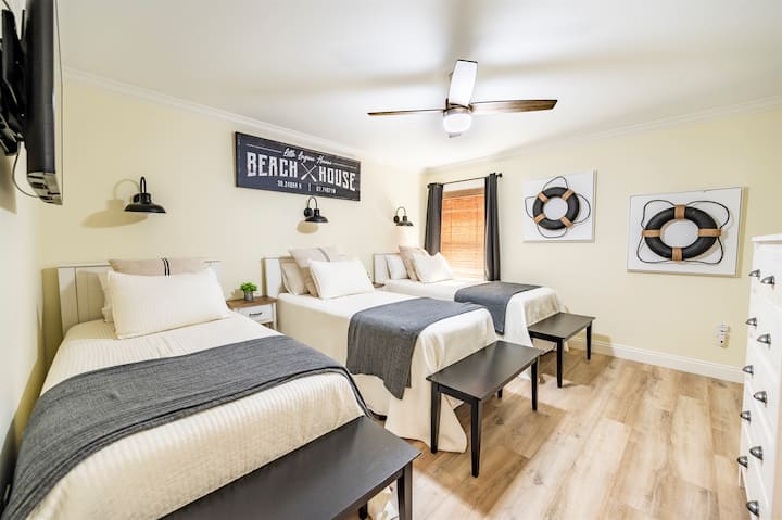 Cozy beach house bedroom with three comfy beds and coastal-inspired decor.