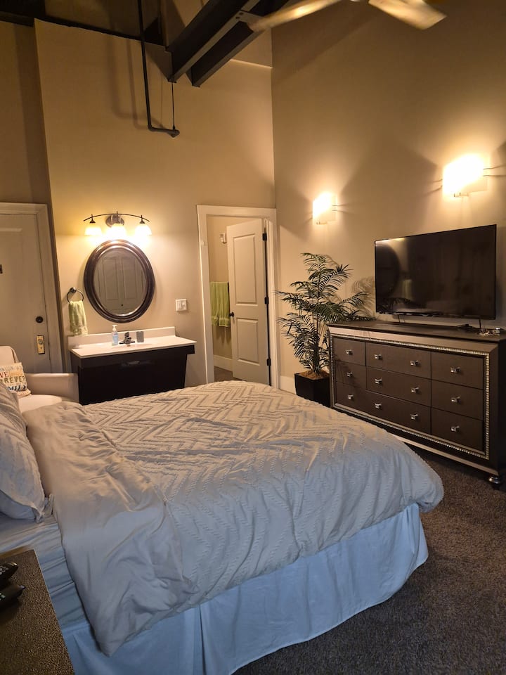 Cama tamaño queen frente a la cómoda y TV de 55"