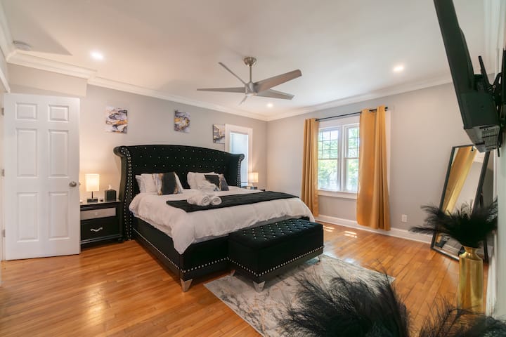 Retreat to pure opulence in this primary suite. Enjoy a massive king bed with a tufted velvet headboard, golden accents, and a large wall-mounted smart TV. High-end comfort designed for an elite sleep experience.