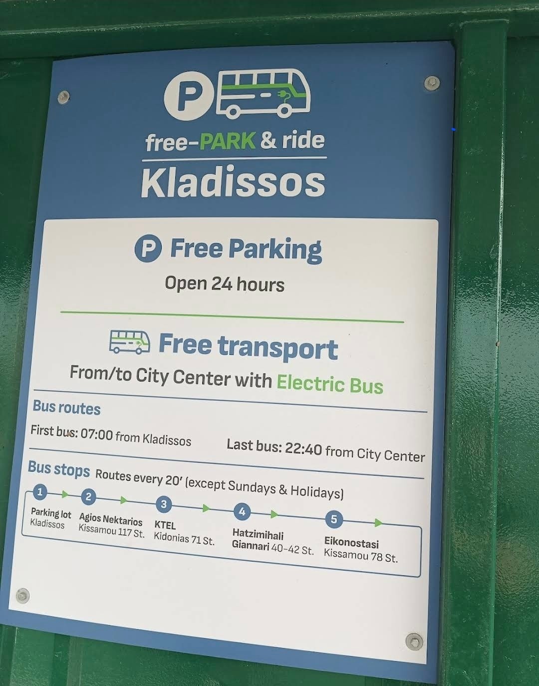 A signage board outlines the free PARK & ride service to Kladissos, detailing free parking and transportation to the city center via an electric bus. The schedule includes early morning departures starting at 07:00 and the last bus at 22:40 from the city.