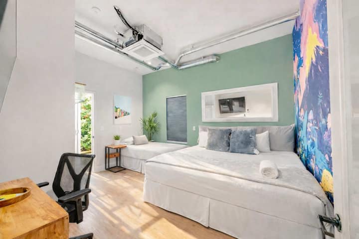 Dormitorio privado accesible según la ADA con cama cómoda, espacio de trabajo dedicado y pared decorada con arte: diseñado cuidadosamente para un fácil acceso, comodidad y una vida relajada en el centro vacacional