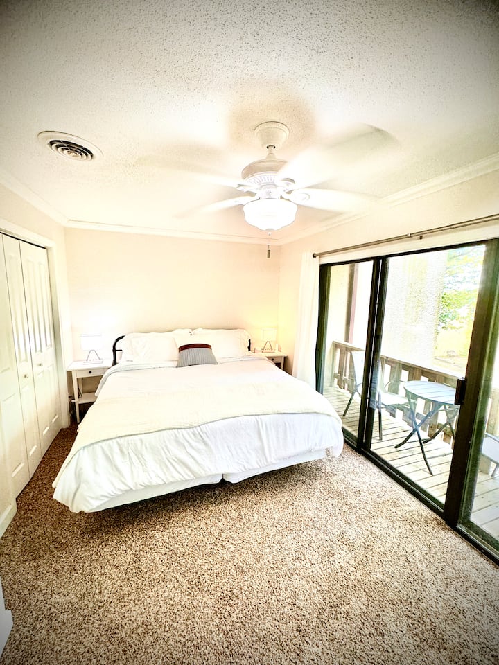 ห้องนอนหลักที่สวยงามพร้อมระเบียงส่วนตัวผ้าม่านสีเข้มในห้องเครื่องเสียงทีวีและโคมไฟระบบสัมผัสข้างเตียงพร้อมที่ชาร์จโทรศัพท์ 