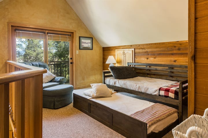 El loft de la planta superior tiene una cama de una plaza con cama corrediza de una plaza, así como su propio televisor inteligente y balcón.