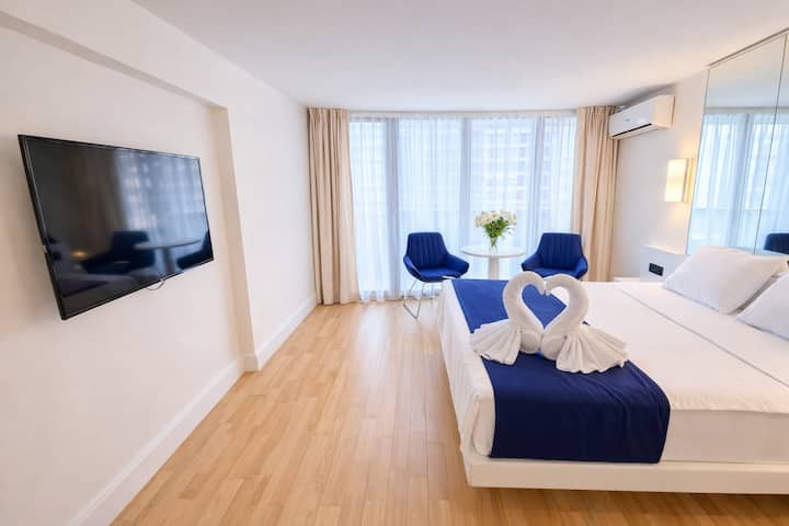 Habitación espaciosa y luminosa con ventanas panorámicas y un interior moderno. Una cama cómoda, una sala de estar y una iluminación suave crean las condiciones perfectas para una estancia cómoda y relajada.