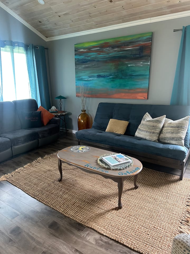Boho-coastal living room: Dual reclining sofa.
Deluxe teal futon. Local art work and an oyster coffee table.