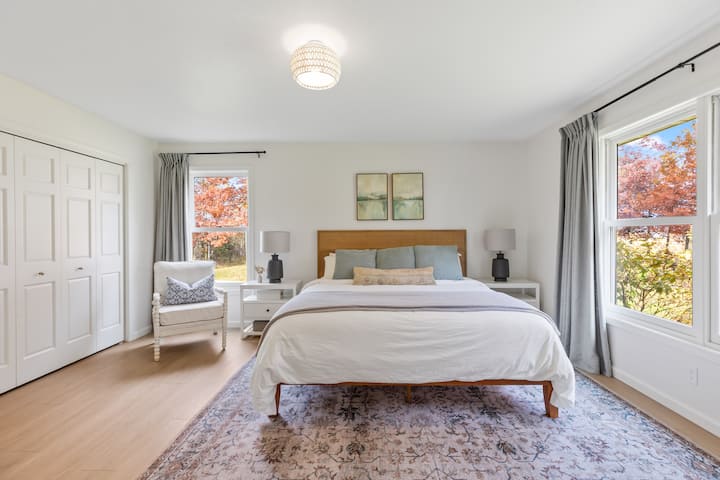 Primary bedroom with King bed, Small Futon, Closet with hangers & Shelves, Attached Bathroom & Room Darkening Curtains. Pack n Play and Bedding for Futon in closet.