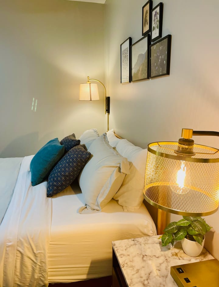 Serene Retreat: Relax in a chic bedroom with queen bed, stylish decor and warm lighting for ultimate comfort!