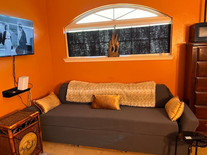 Sala de estar y cocina pequeña en la planta superior, con escritorio, microondas, freidora de aire y cómodo sofá.