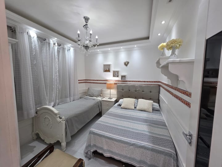 Chambre 2 équipée de la climatisation, d'un lit double et d'un lit simple, d'une table de chevet, d'une télévision connectée, de rideaux occultants, d'une table à langer, d'un fauteuil, de literie, d'une couverture et d'oreillers supplémentaires, ainsi que d'un fer à repasser.